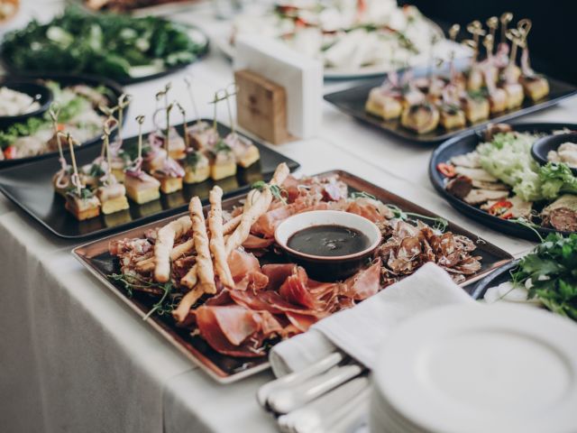 Smoked meat,sauce,prosciutto, salad appetizers on table at wedding or christmas feast. Luxury catering concept. Delicious italian food table at wedding reception.